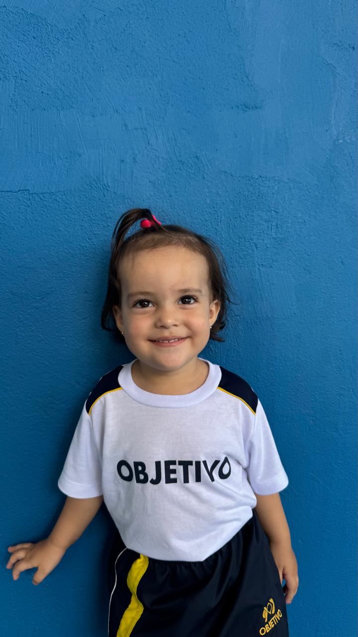 Aluna da Educação Infantil sorrindo com uniforme do Objetivo